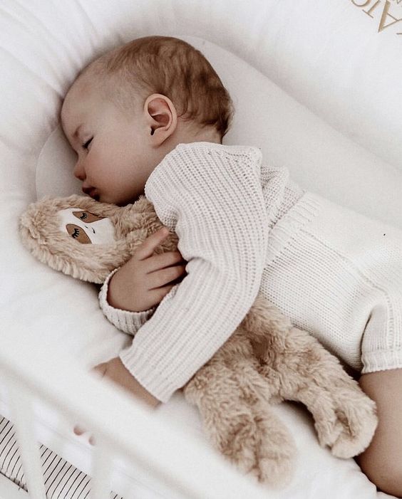 Bébé dui dort dans son lit avec sa peluche dans les bras