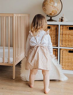 enfant jouant à coté de son lit bébé avec tapis poilu