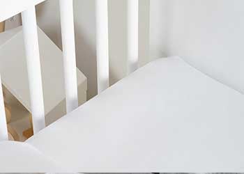 draps dans lit bébé à barreaux blanc