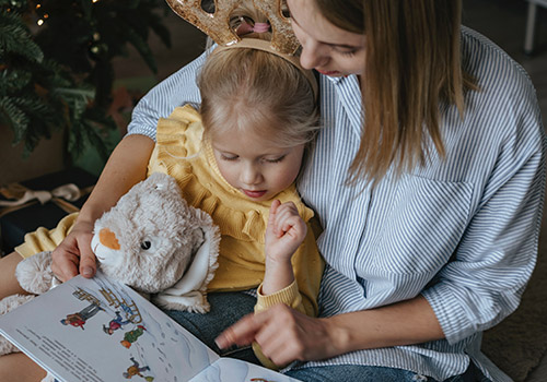 Femme lisant une histoire à petite fille blonde sur ses genoux